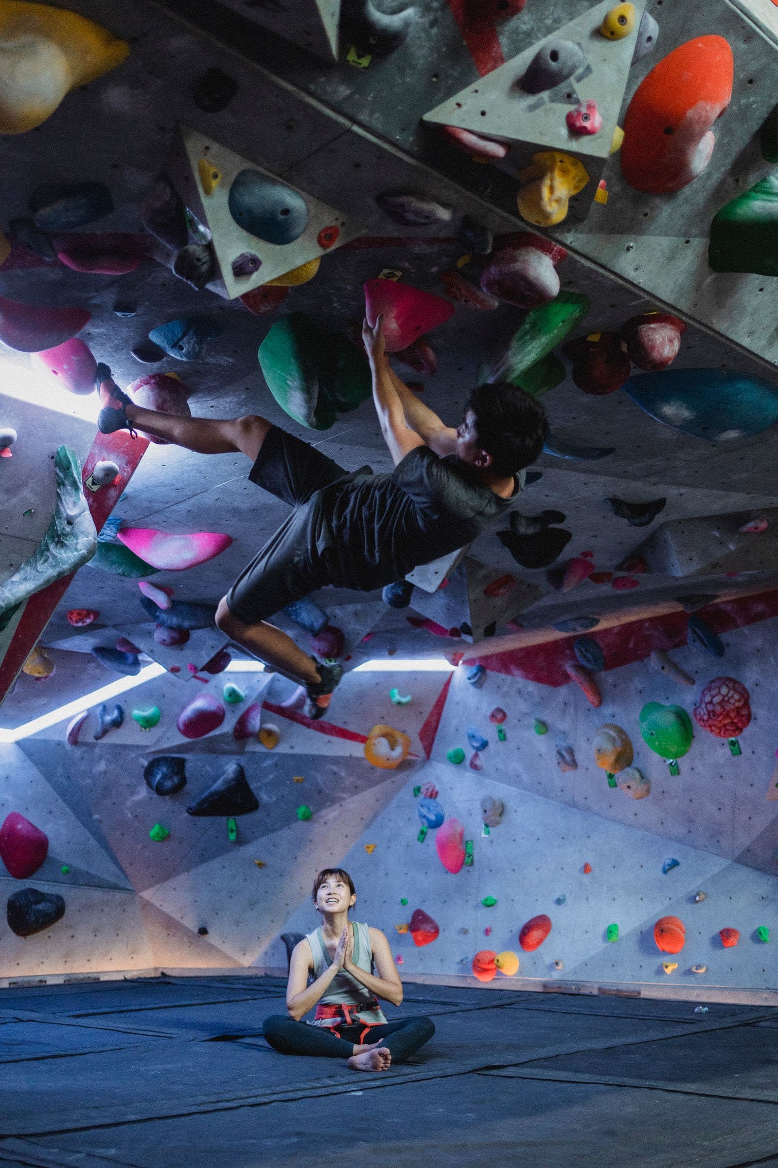 Climber reaching for a hold on a colorful indoor bouldering wall