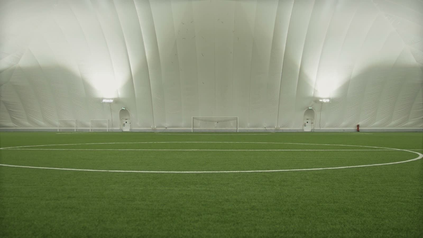 Empty indoor soccer dome with pitch lines and goals set up before the first booking of the day