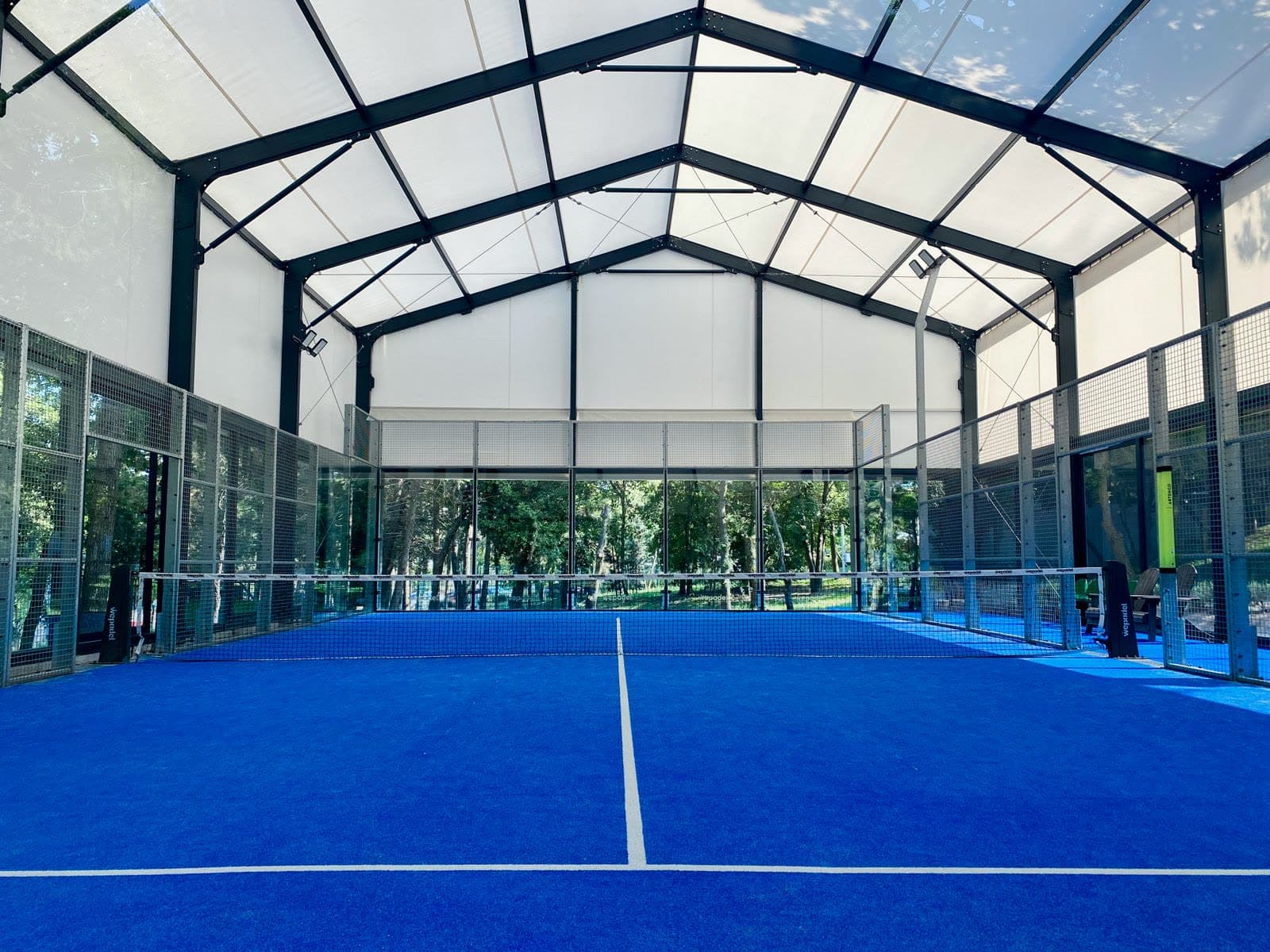 Empty indoor padel court with blue surface and glass walls