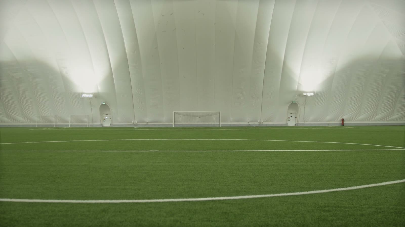 Empty indoor soccer dome interior with no players during a quiet, off-peak hour