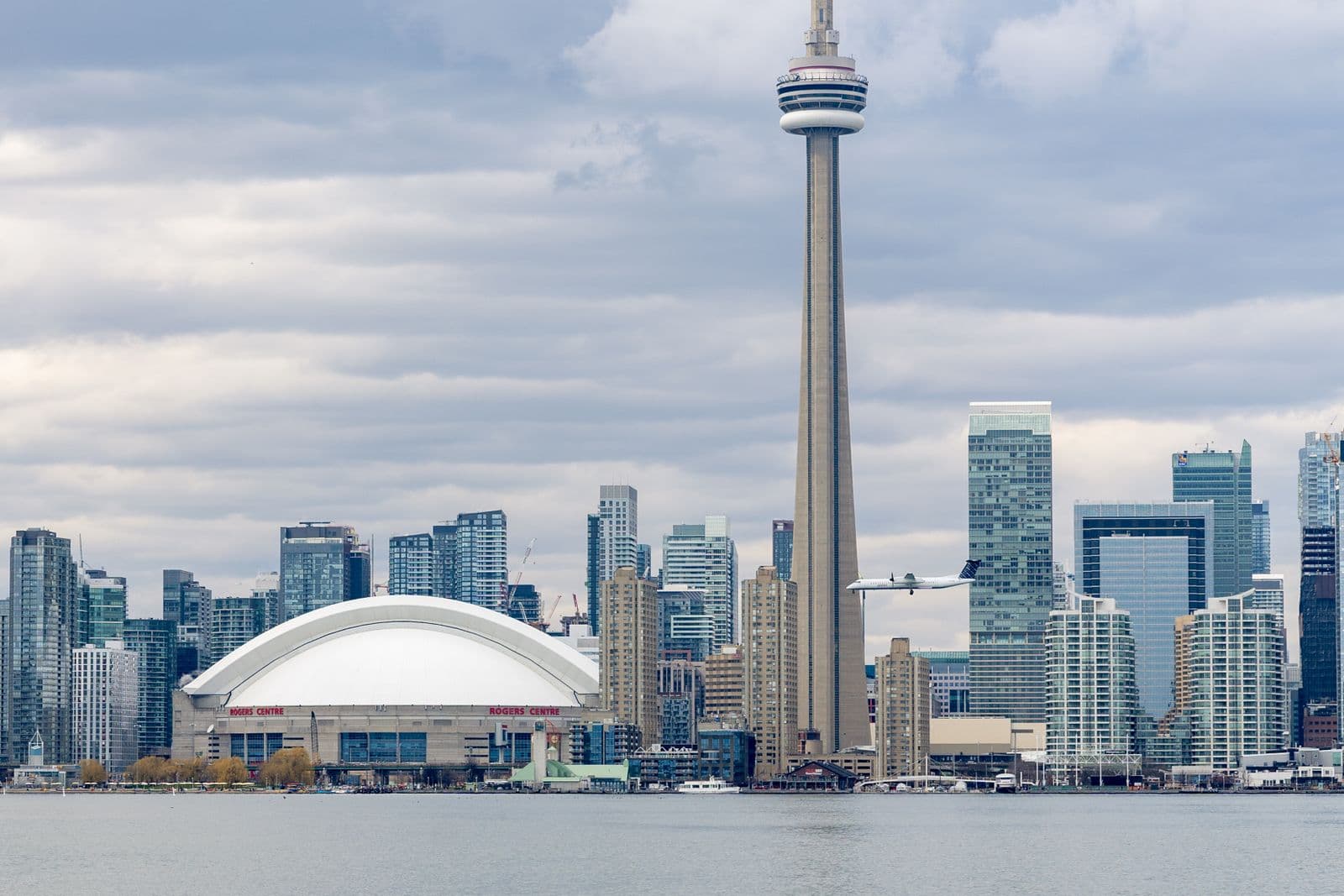 Toronto skyline with the CN Tower and Rogers Centre viewed from the waterfront under a cloudy sky